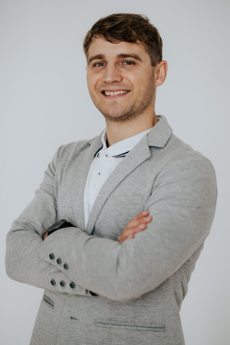 Mężczyzna, laureat programu stypendialnego UAM uśmiecha się.